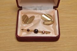A yellow metal bar brooch having three graduated garnets in claw settings, marked 9ct to reverse,