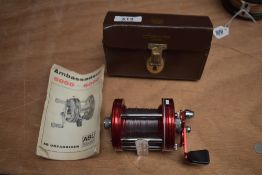 An Abu Ambassadeur multiplier reel 6000 in red with original leather case and instructions