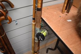 Four vintage fishing rods including fibreglass one has a Penn 150 reel attached