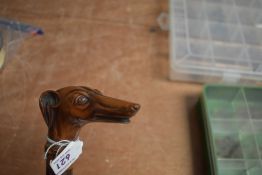 A vintage walking cane with a carved greyhound dogs head. It has been broken around the collar