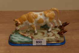 A Continental porcelain cow study, modelled in a naturalistic setting and hand decorated in