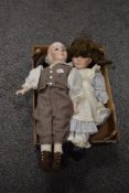 Two 20th century bisque head dolls with glass eyes and jointed limbs, dressed in traditional