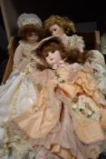 Four modern bisque headed dolls having material bodies.