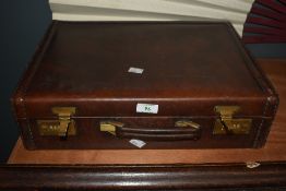 An early to mid-20th Century stitched brown leather suitcase with combination locking system and