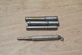 A Small white metal propelling pencil with ribbon loop and three lead cases one with leads