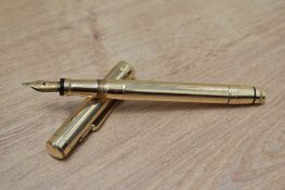 A Mabie Todd twist fill fountain pen in yellow metal engine turned reeded design having Swan 2 14ct