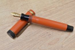 A Parker Duofold Junior Lucky Curve button fill fountain pen in orange with raised band to the cap
