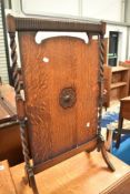An early 20th Century oak fire screen having barley twist supports and applique decoration