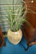 A reproduction urn with imitation grass and silvered twigs