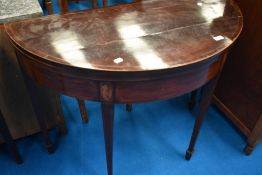A 19th Century mahogany fold over card table of demi lune form having line inlay , on square tapered