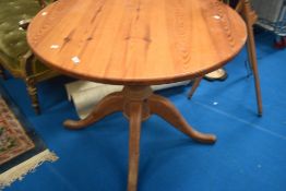 A vintage pine kitchen table of circular form on turned column and triple splay legs, diameter