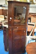A period oak corner cupboard having glazed top section with enclosed panelled lower section,