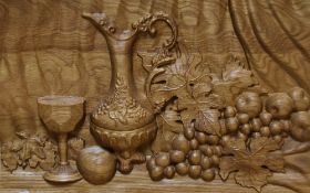 20th Century, an attractive light oak panel carved in relief with a still life scene, measuring 35cm
