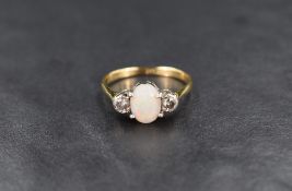 A three stone opal and diamond ring having central matt opal cabochon in a four claw setting flanked