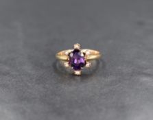 A yellow metal amethyst and seed pearl ring marked 9ct, the central oval cut amethyst measuring