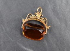 A 9ct gold mounted spinner fob, the decorative scroll mount set with an orange paste spinner, 5.1g
