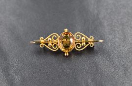 A small yellow metal bar brooch stamped 9ct having a central citrine within a decorative mount,