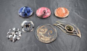 A small material covered jewellery case containing seven white metal brooches most stamped silver,