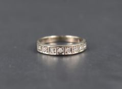 A white metal half eternity ring stamped 18ct having eight diamond chips in square mounts, size