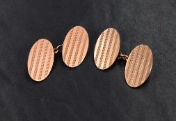 A pair of 9ct rose gold cufflinks of oval form having stripe decoration and chain connectors, approx
