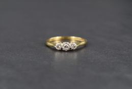 A diamond trilogy ring having three small stones in an illusionary setting on a yellow metal shank