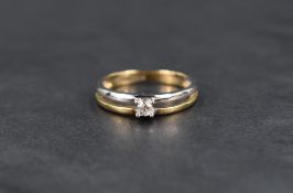 A small diamond solitaire ring, approx 0.10ct in an open 9ct white and yellow gold split band,