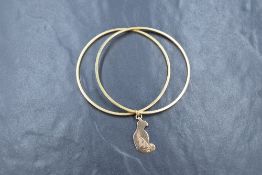 A pair of yellow metal bangles marked 750, joined with a sitting cat charm marked 9ct, 7.7g gross