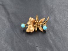 A yellow metal and turquoise brooch, the floral design set with cabochon turquoise marked K18,