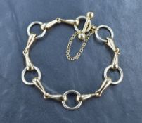 A 9ct two tone gold horse bit style bracelet with barbell closure and safety chain, 27g