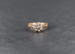 A diamond cluster ring, the irregular cut diamonds set in a daisy motif, with small scroll