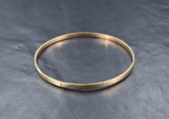 A yellow metal bangle, marked 9ct having alternating panels of textured and plain design,