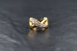 A yellow metal wave motif ring, having a cubic zirconia set feather, marked '666' with another