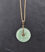 A Chinese jade disc pendant with 14ct gold mount and central Chinese character, on a 9ct gold chain,