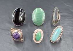 Six oversized polished stone rings all set in white metal, presumed silver