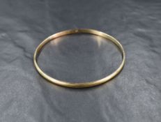 A yellow metal bangle, marked 9ct of rounded design having line engraving, approximately 20cm