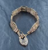 A rose metal five bar gate bracelet marked 9ct, having a heart padlock and safety chain,