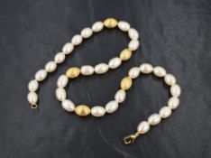 A baroque pearl necklace having oval pearls and five gold plated matching spacer beads, approx 16'