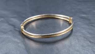 A 9ct gold two-tone hinged bangle, the two bands joined with horizontal bar, with safety clasp, 5.
