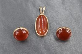 An oval yellow metal bezel set carnelian pendant, along with a pair of yellow metal bezel set