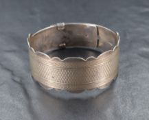 A white metal belt style bangle having engine turned decoration and scalloped edges, marked Sterling