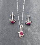 A 14ct white gold ruby and diamond set, comprising a necklace and stud earrings, the oval cut rubies