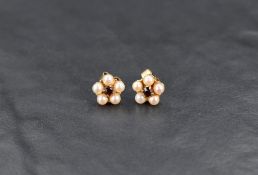 A pair of 9ct gold pearl and garnet stud earrings, the central garnets with a pearl border in a