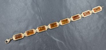 A 9ct gold and Baltic amber bracelet having eight articulated rectangular panels, approx