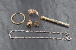 A small selection of 9ct gold and yellow metal jewellery including a tie slide, odd earrings and a