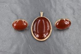 A large yellow metal carnelian set pendant, along with a pair of yellow metal bezel set carnelian