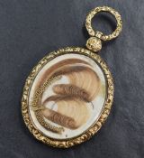 A Victorian glass hair locket having to decorative hair panels within a moulded yellow metal