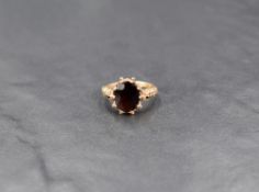 An oval garnet ring in a claw set moulded mount on a 9ct gold loop, size J & approx 3g