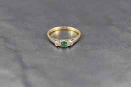A three stone diamond and emerald ring, the central small square emerald flanked by two pave set