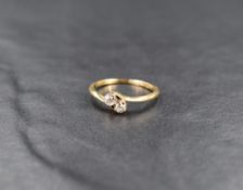 A diamond trio ring, each stone approx 0.05ctin claw set mounts to crossover shoulders on a yellow