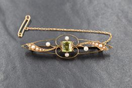 A 15ct gold bar brooch, the open work design with a centrally set square cut peridot, flanked by
